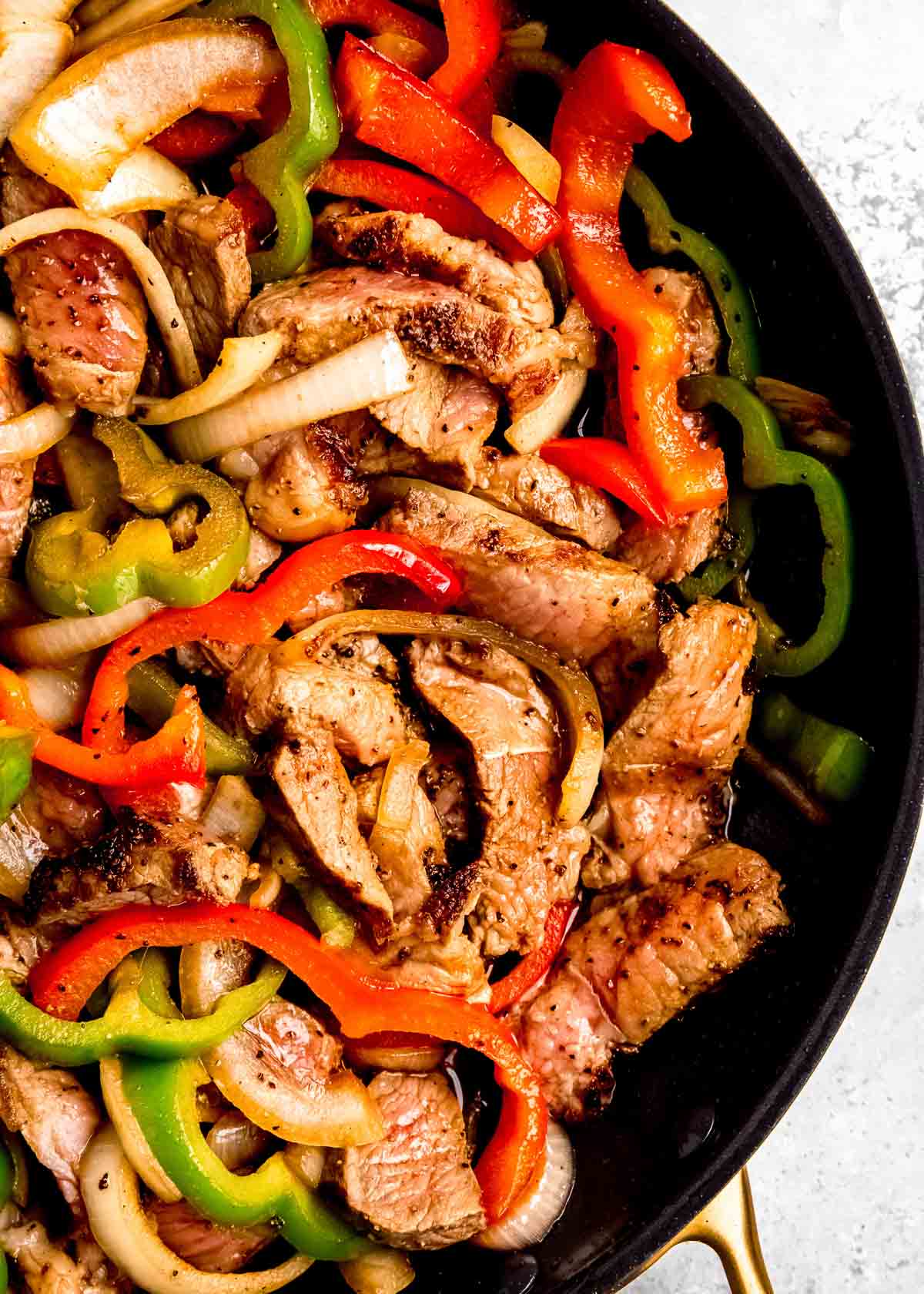 close up, overhead image of steak and peppers in skillet