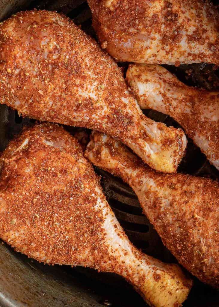 seasoned chicken legs in the basket of an air fryer