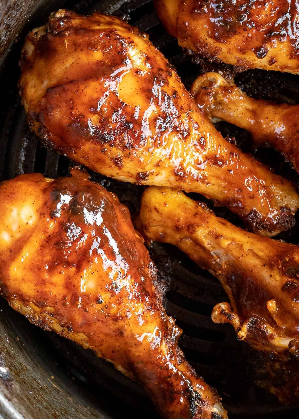 chicken legs brushed with bbq sauce in the air fryer basket