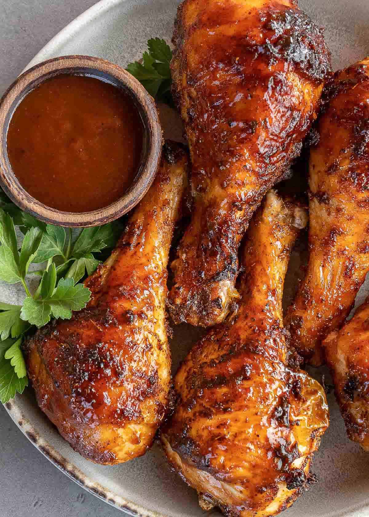 juicy bbq chicken drumsticks with a side of bbq sauce on a plate