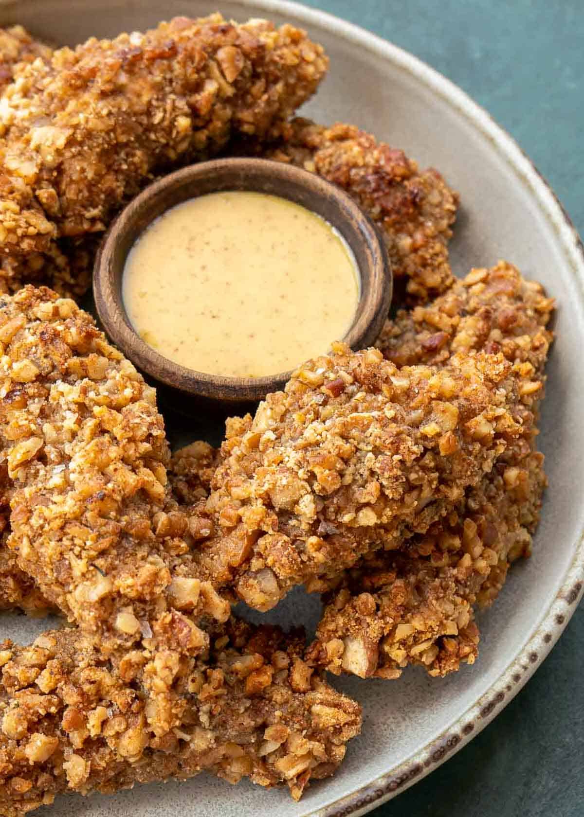 crunchy, crispy pecan chicken strips on a plate with dipping sauce