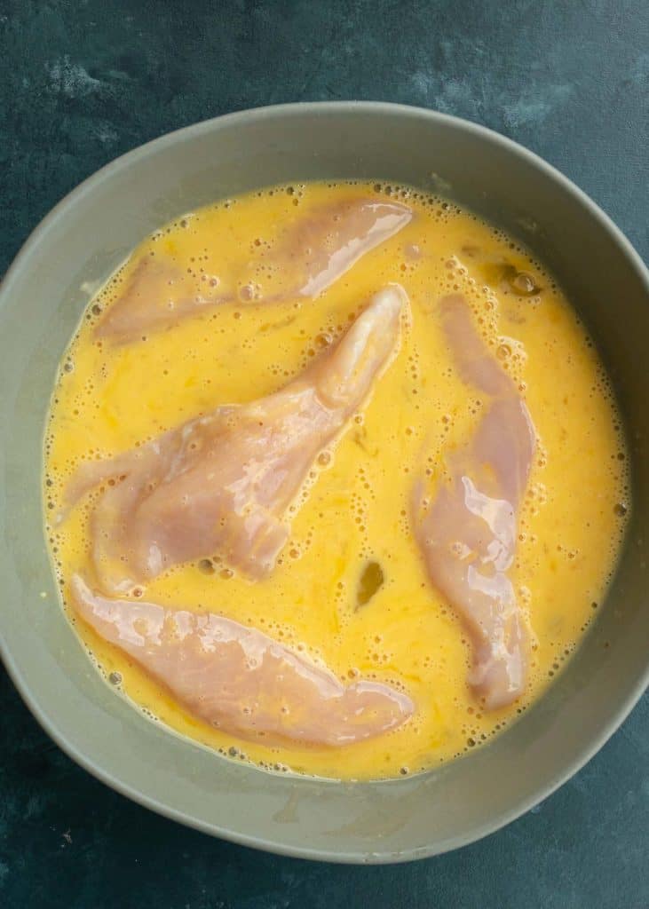 chicken strips in the egg mixture in a shallow bowl