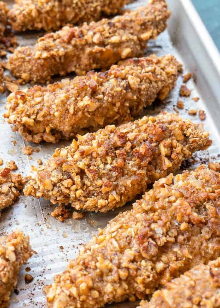 closeup view of cooked, crispy pecan crusted chicken on a baking sheet