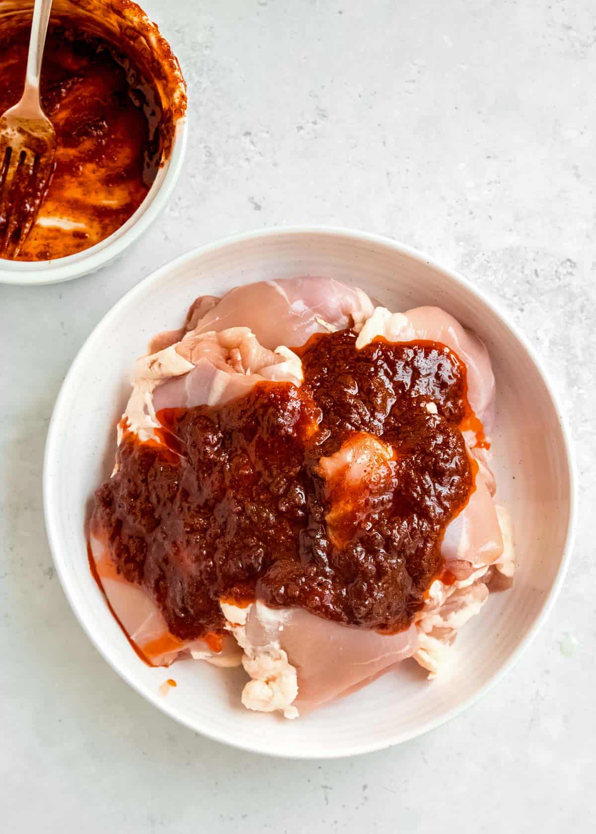 chicken thighs in a white bowl, covered in a homemade chipotle marinade