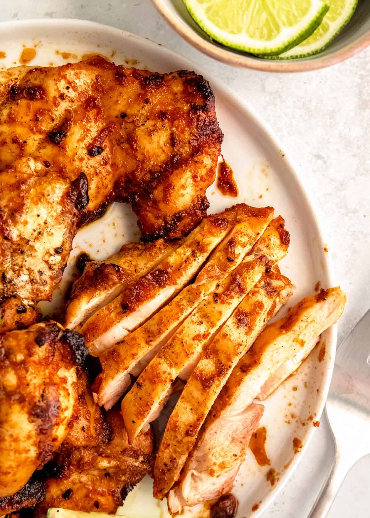 a platter of easy grilled chipotle chicken, some sliced, some whole