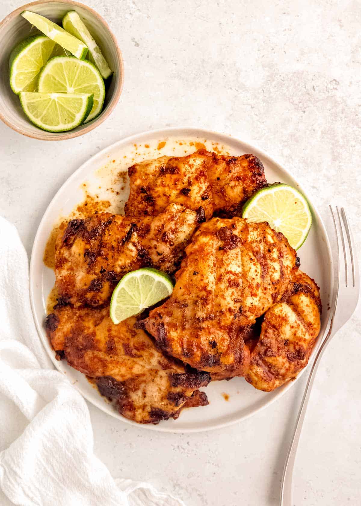 overhead shot showing a platter of chipotle grilled chicken with lime wedges