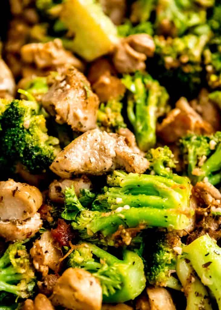 closeup of tender broccoli florets and juicy chicken bites coated in a seasoned garlic butter sauce