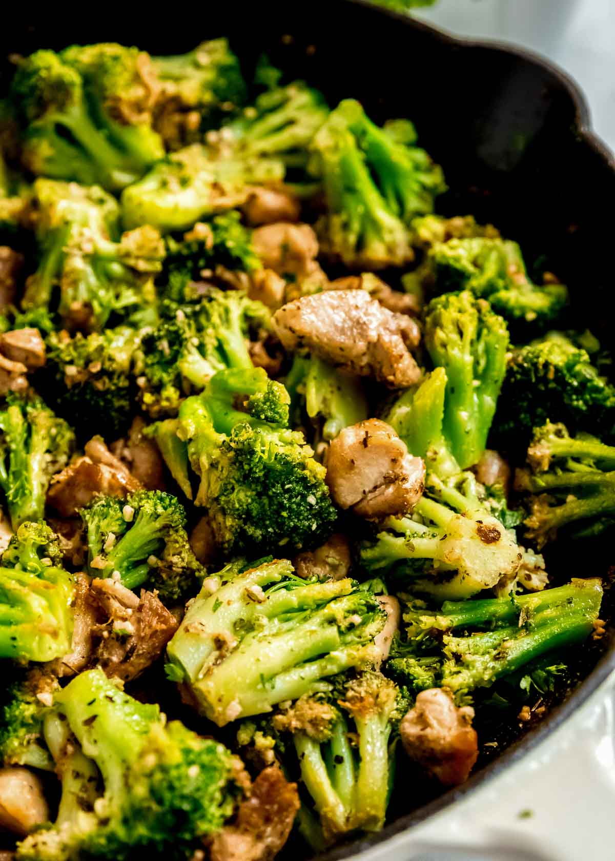 a large skillet filled with chicken and broccoli coated in garlic butter.