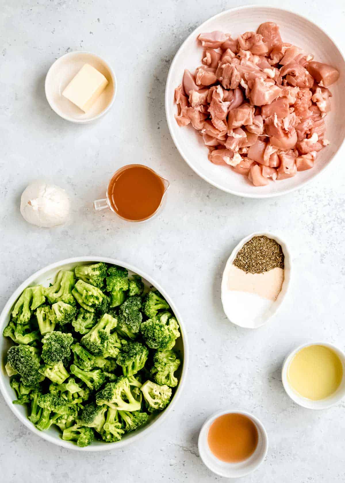 all ingredients needed for garlic butter chicken and broccoli on a white background