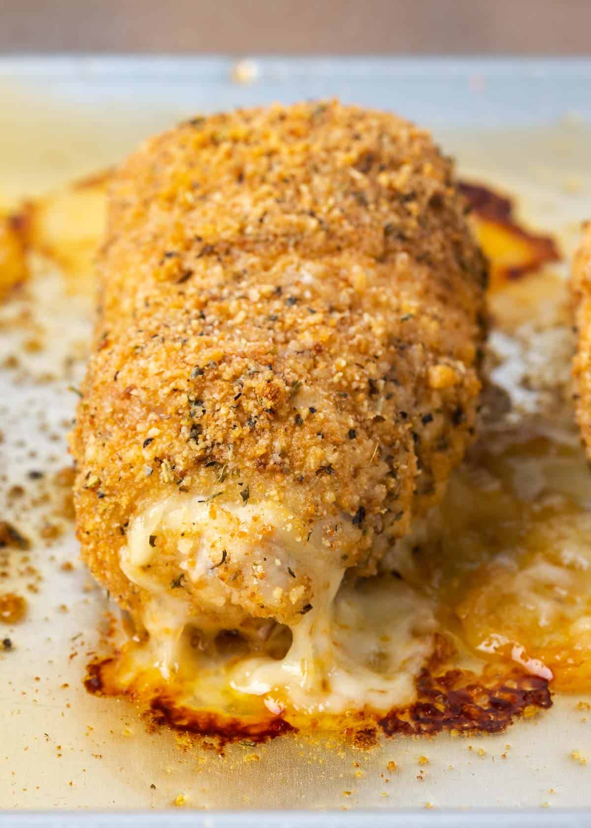 closeup view of a cooked pepperoni and cheese stuffed chicken roll on a baking sheet