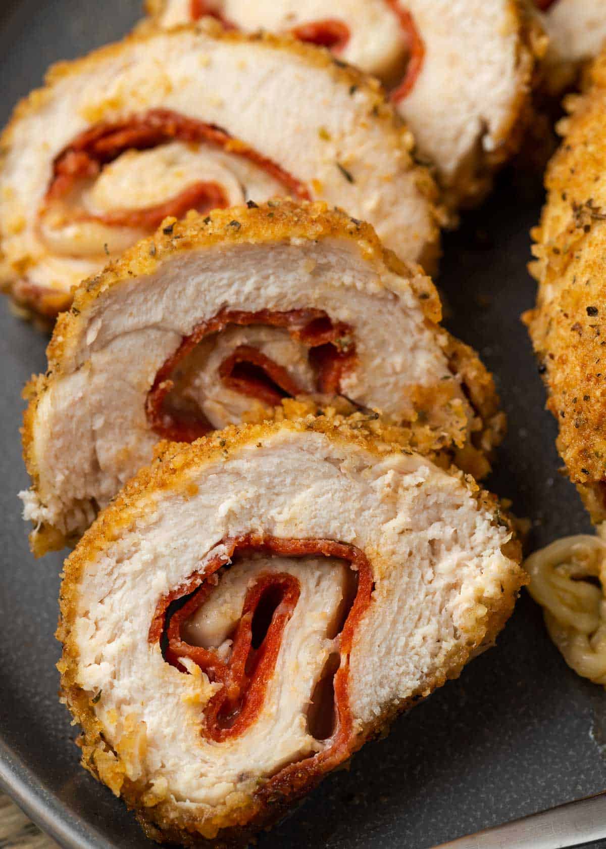 closeup view of slices of rolled up chicken stuffed with pepperoni and mozzarella