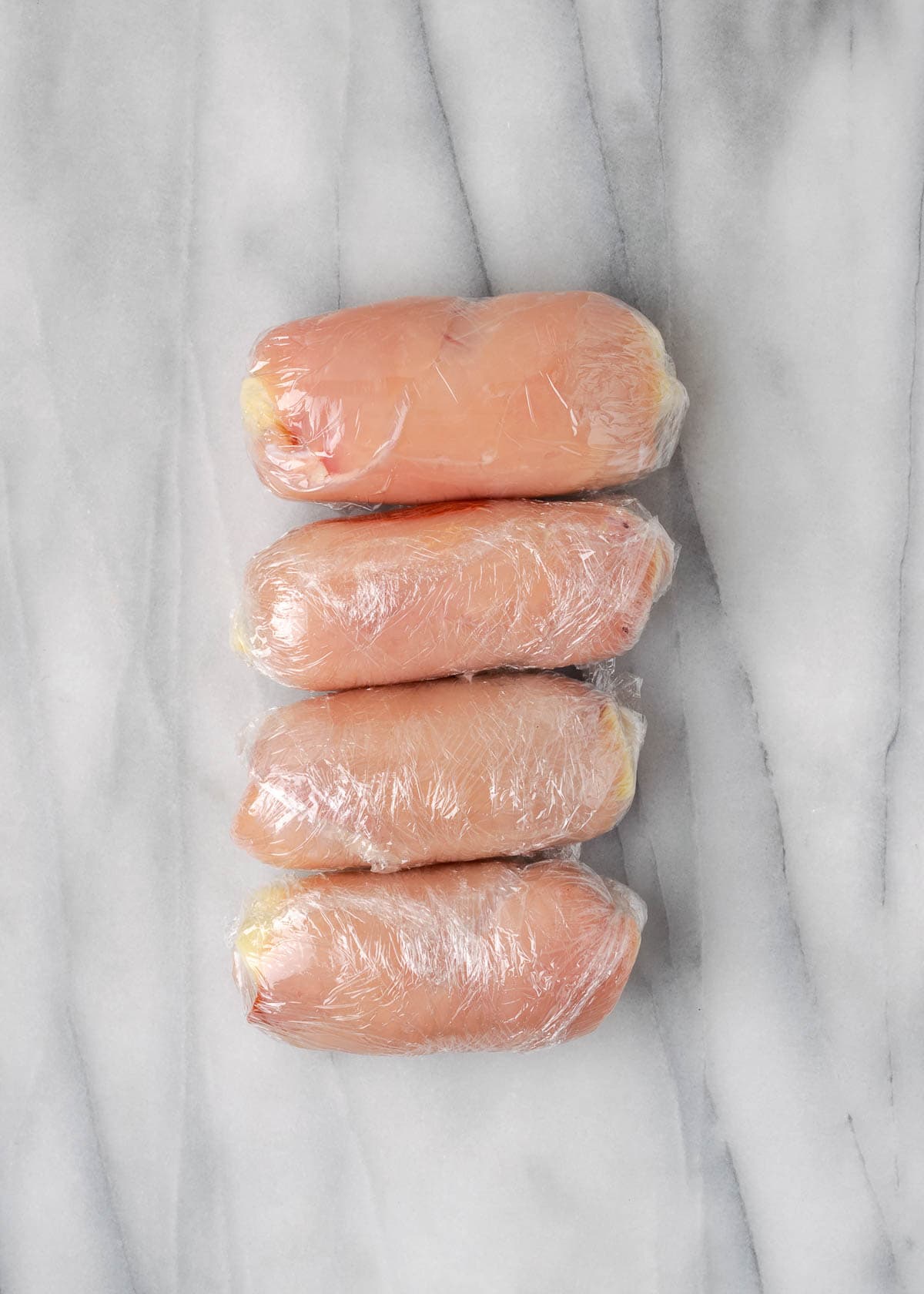 four stuffed chicken rolls in plastic wrap