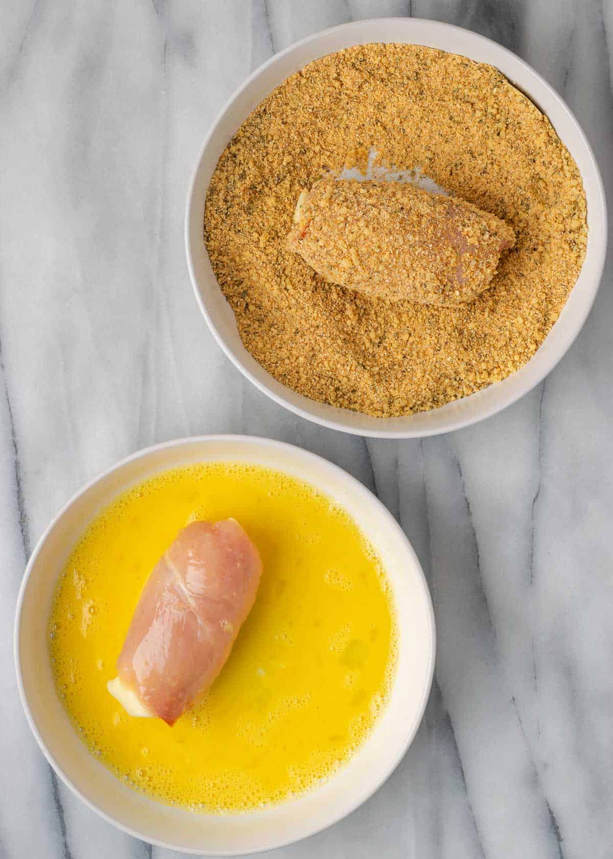 a chicken roll in each of the shallow bowls in the breading station