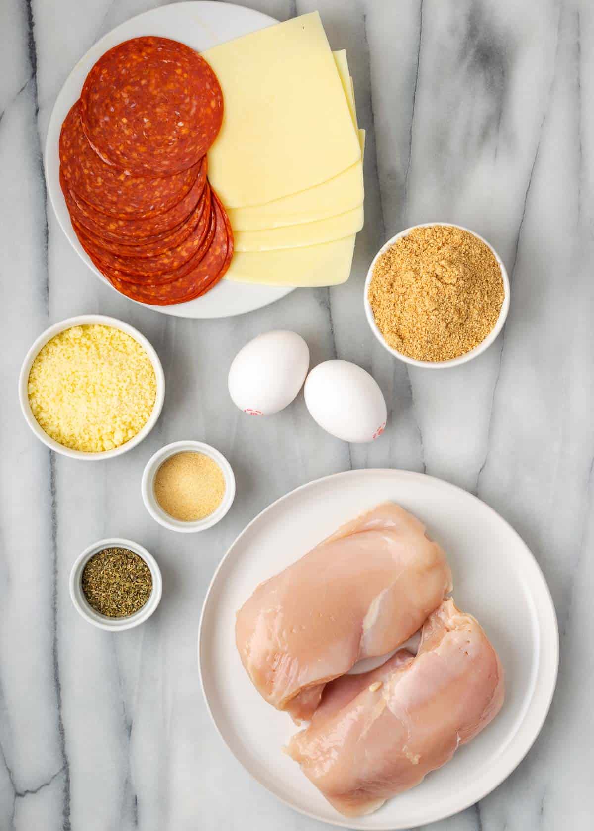 ingredients for pepperoni and cheese stuffed chicken on a marble background