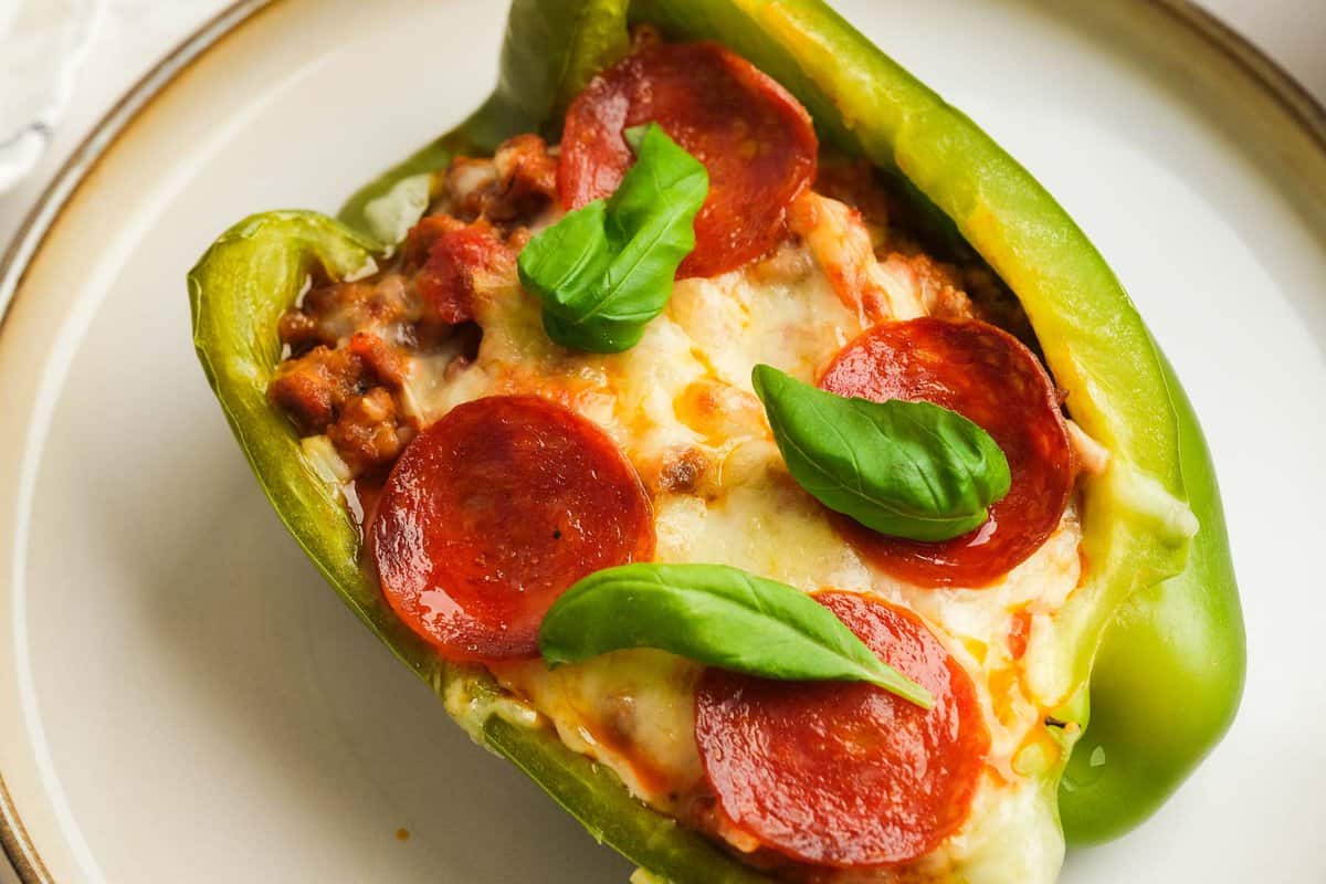 closeup horizontal shot of a pizza stuffed pepper with crispy pepperoni, fresh basil, and melted mozzarella on top