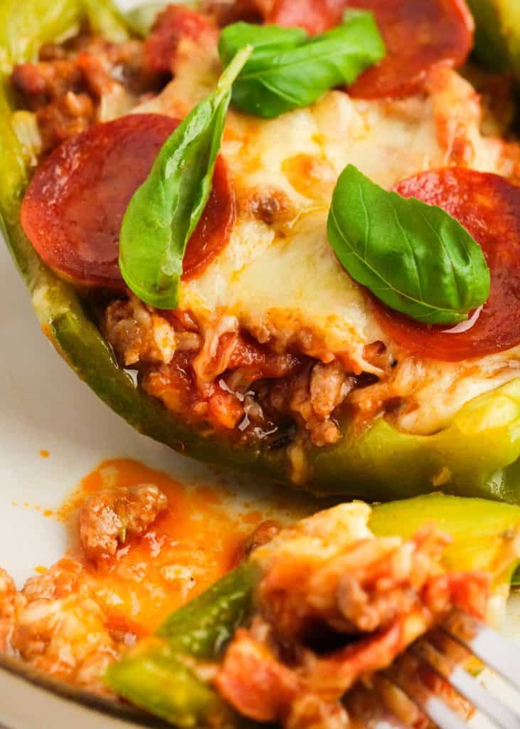 a closeup view of a big bite of pizza stuffed pepper on a fork with italian sausage and melty mozzarella