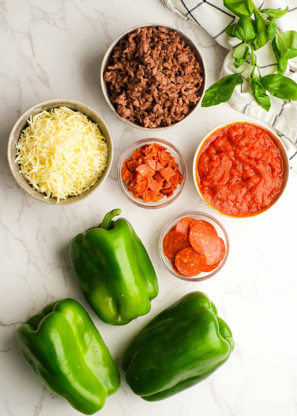 ingredients needed for pizza stuffed peppers in individual bowls on a white background