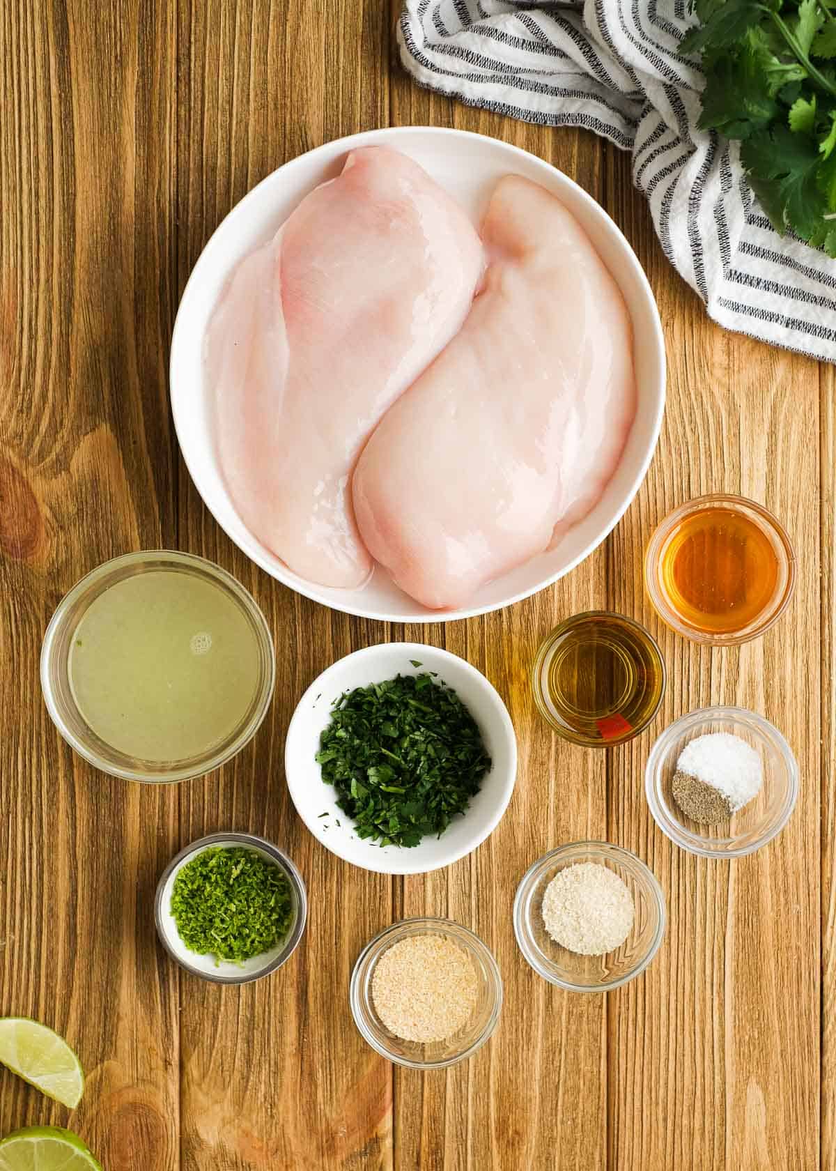 ingredients for the best cilantro lime chicken on a wooden cutting board