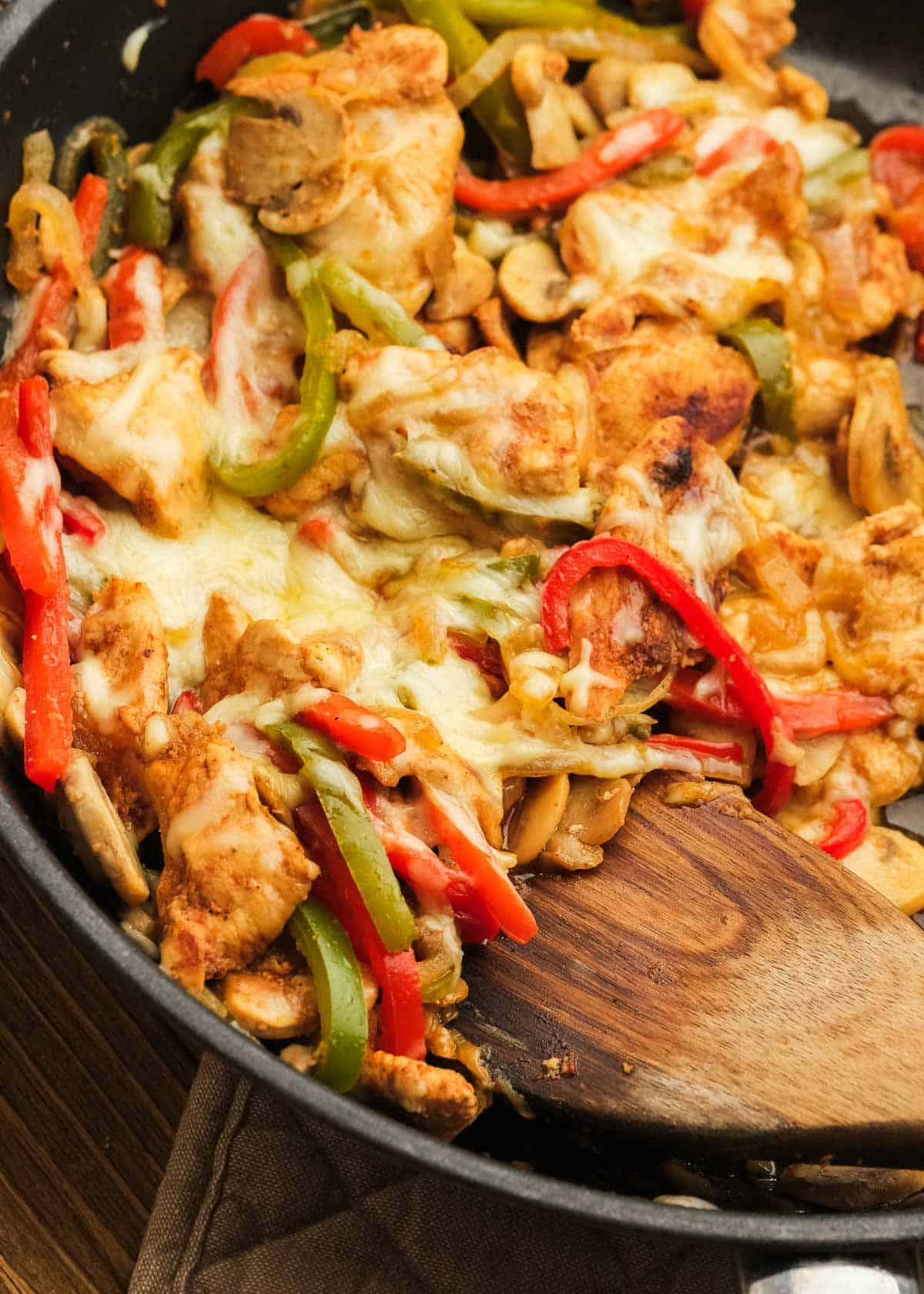 overhead image of a scoop of cheesesteak skillet being removed from cast iron pan