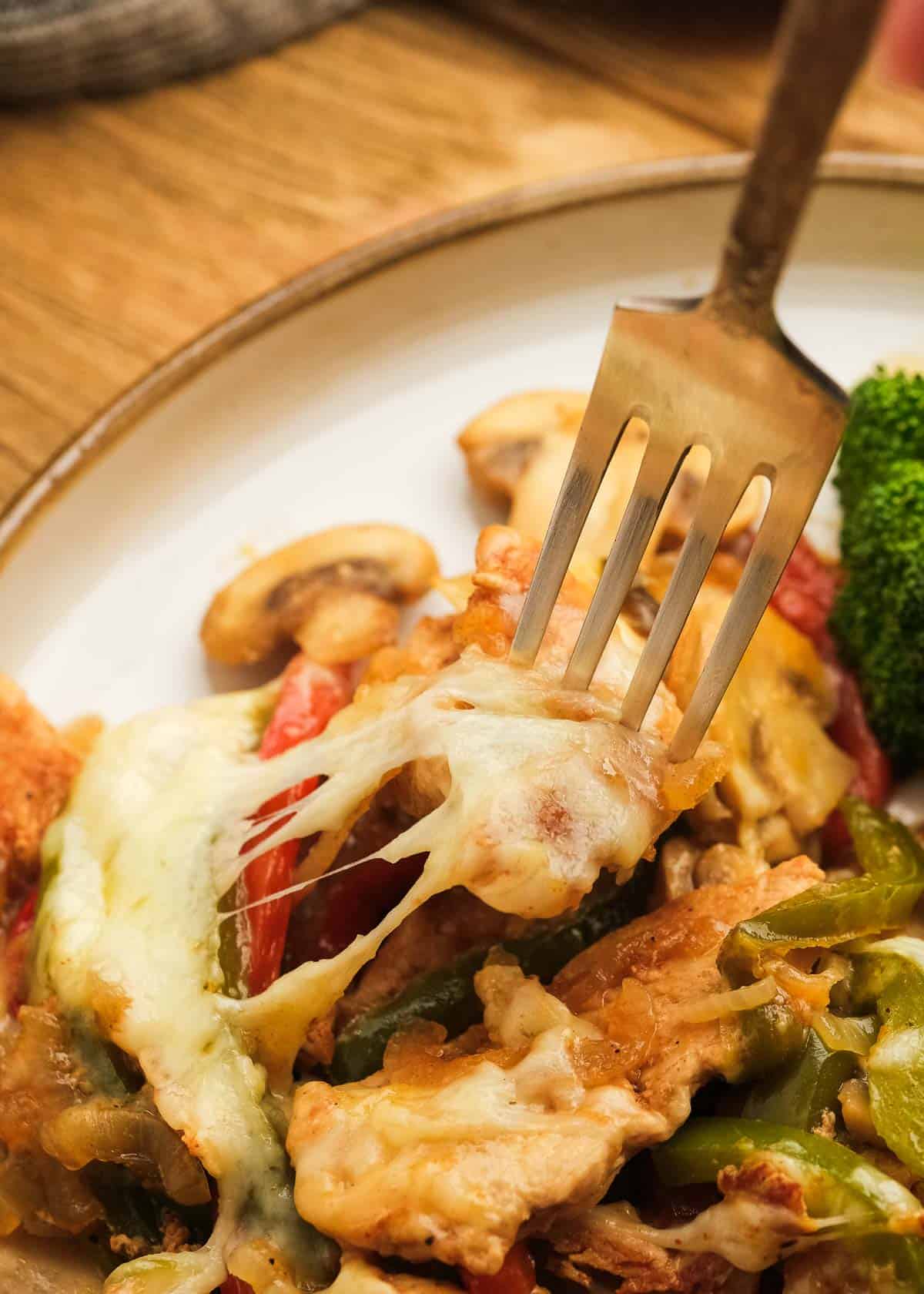 close up image of cheesesteak and fork on white plate