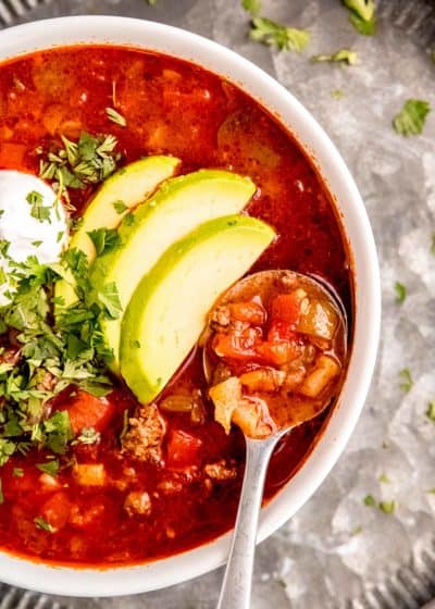 overhead image of taco soup in white bowl on silver platter with silver spoon