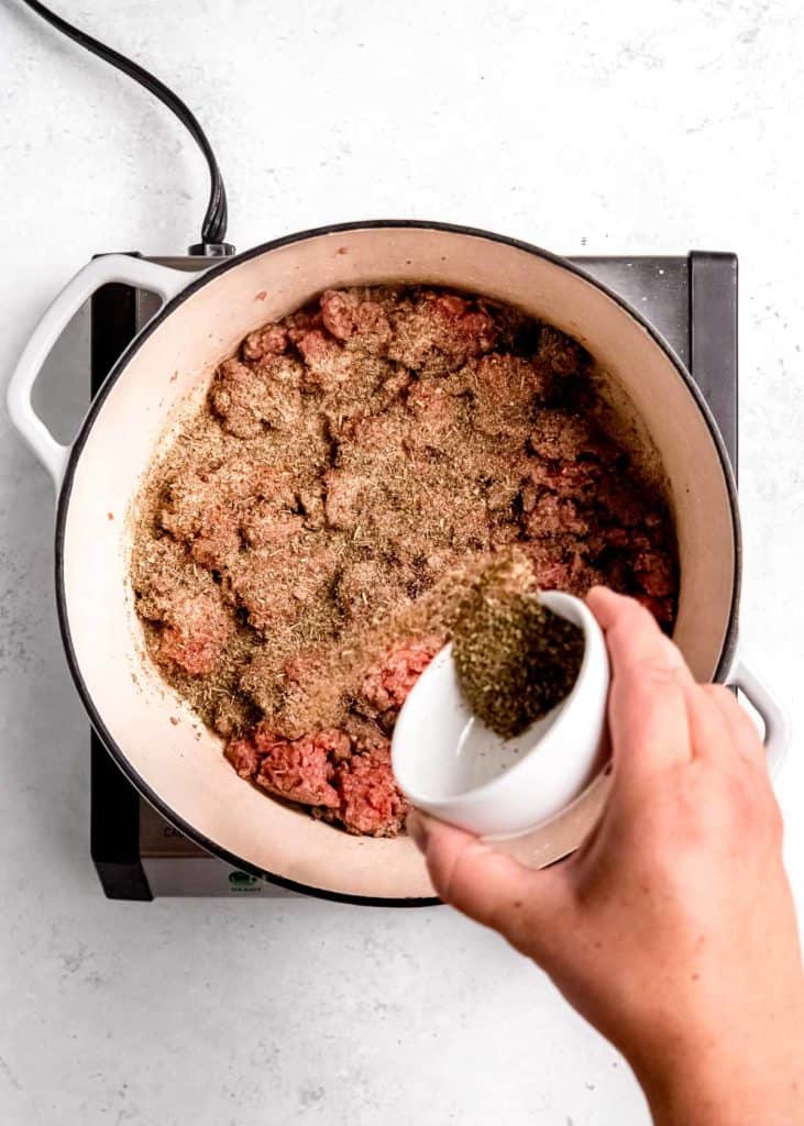 spices being added to ground beef in dutch oven