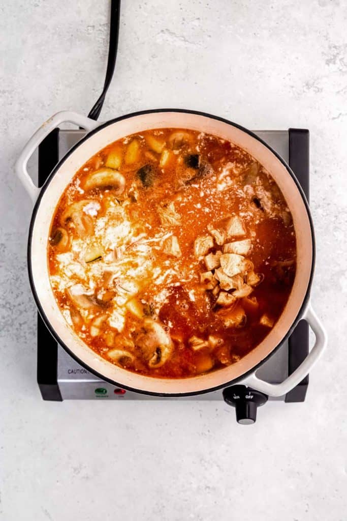 overhead image of curry paste being added to thai curry chicken soup