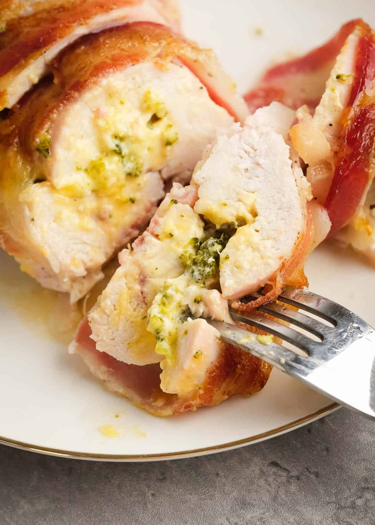 a piece of sliced bacon wrapped stuffed chicken on a fork