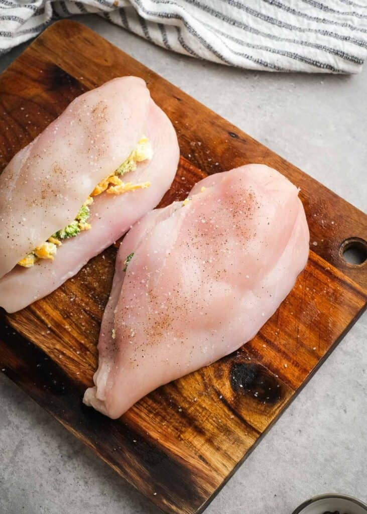 raw stuffed chicken breast on wooden cutting board