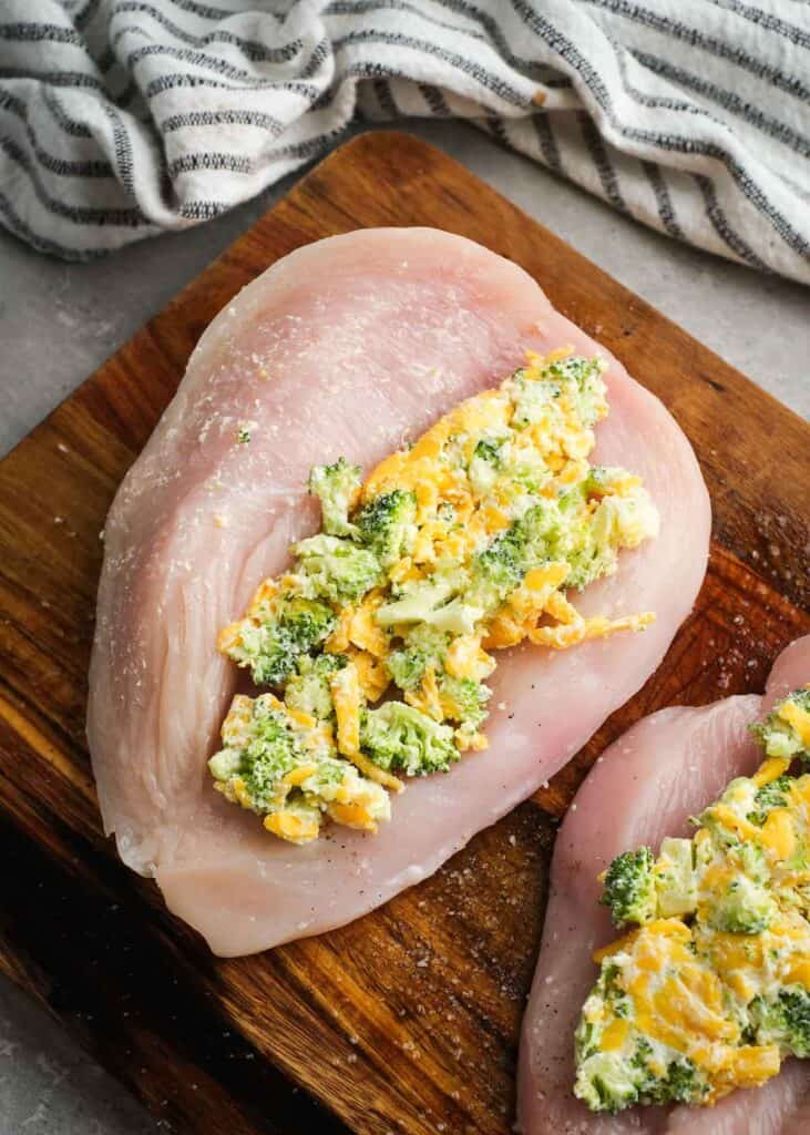 butterflied chicken breast with stuffing mixture on wooden cutting board