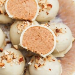 close up image of a sliced almond butter truffle stacked on top of more almond butter truffles