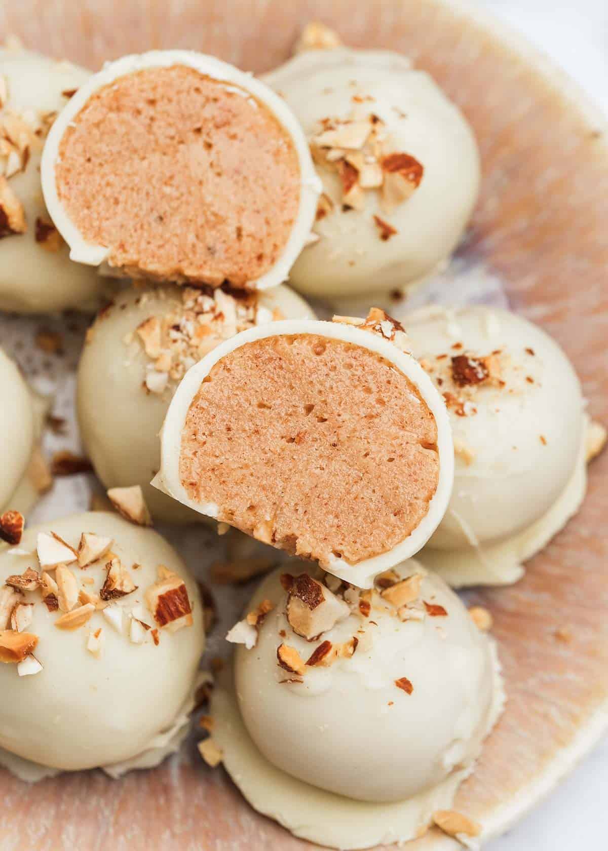 close up image of a sliced almond butter truffle stacked on top of more almond butter truffles