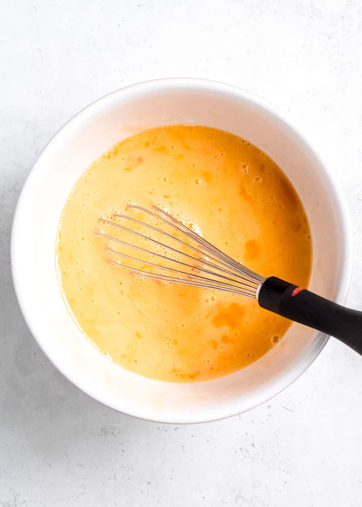 eggs being whisked in a white mixing bowl
