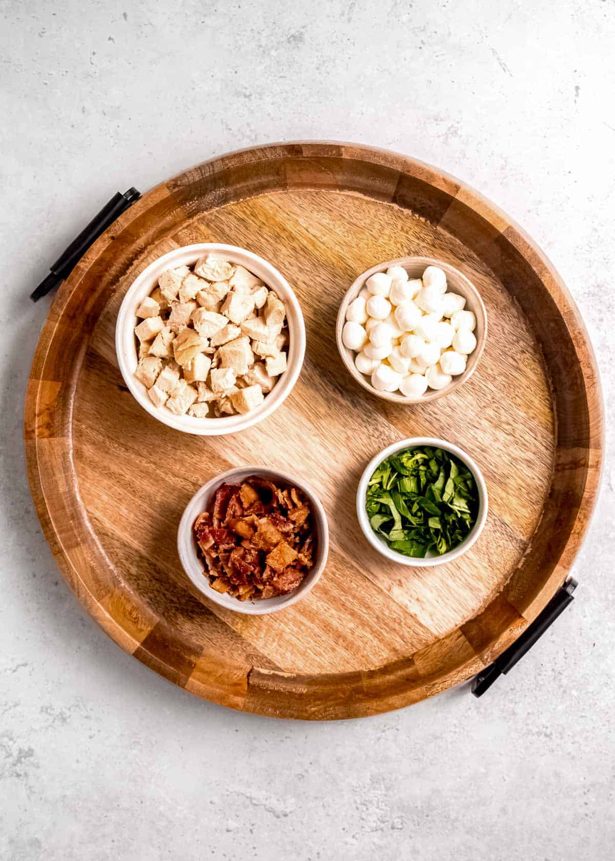 bacon, mozzarella, and chicken on a wooden cutting board