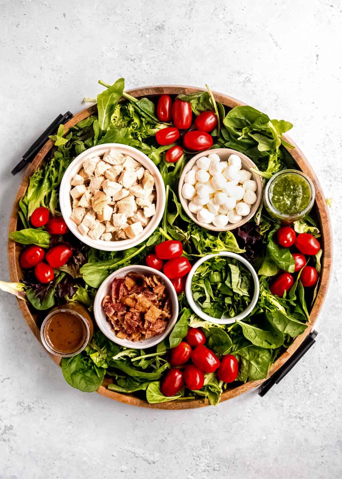 overhead image of caprese salad board on wooden serving board on white table