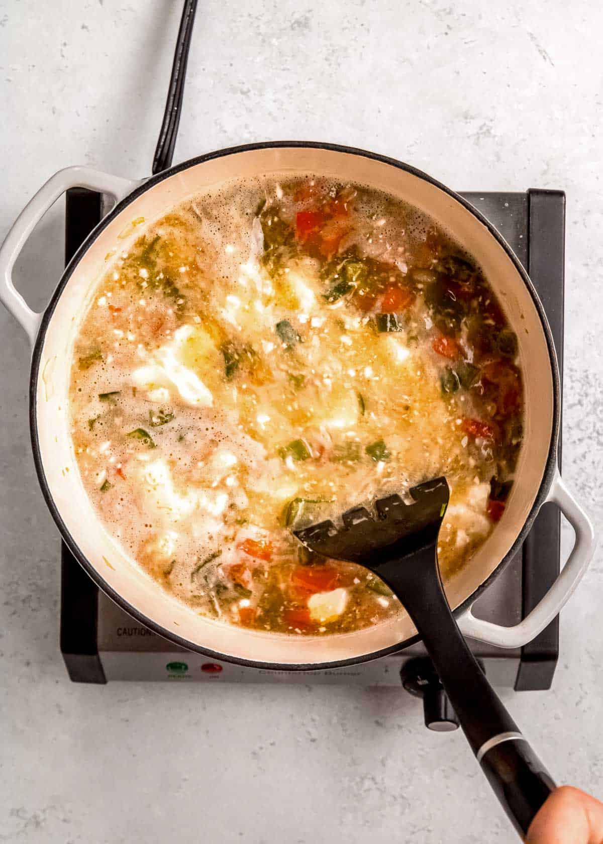 chile relleno soup ingredients being stirred in dutch oven