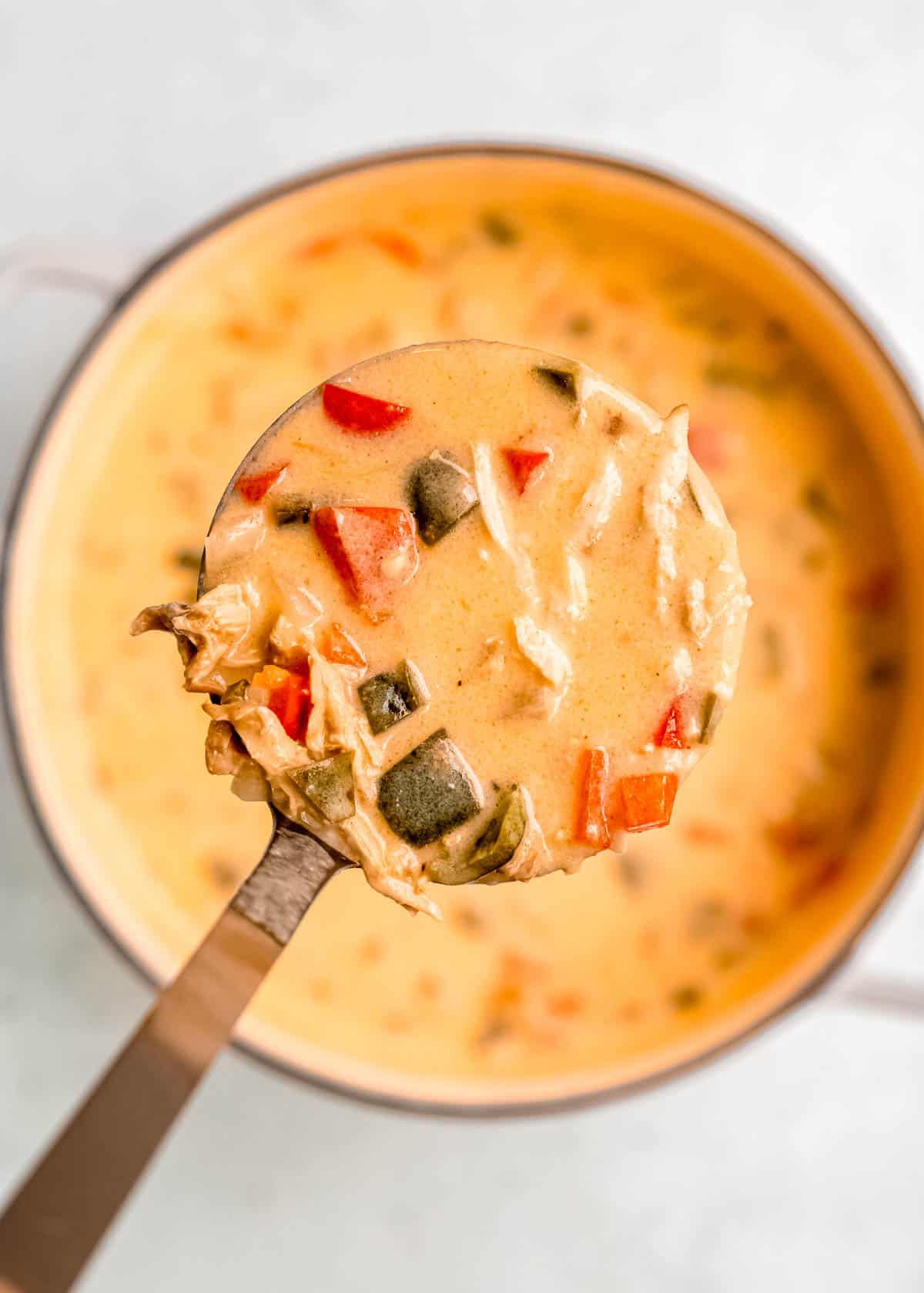 close up image of a spoonful of chile relleno above dutch oven full of soup