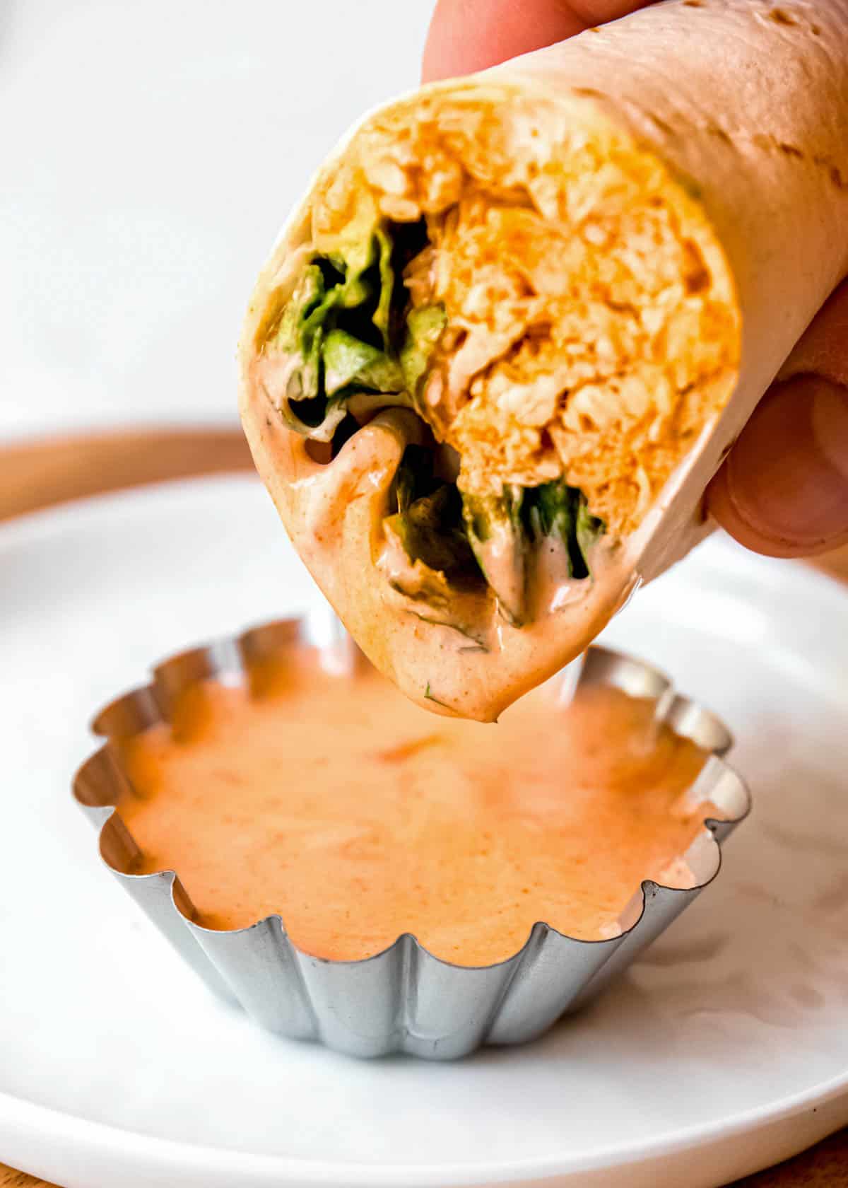 buffalo chicken wrap being dipped in buffalo sauce