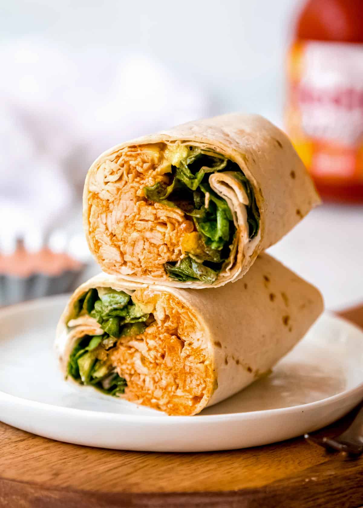 a buffalo chicken wrap cut into two pieces sitting on a white plate