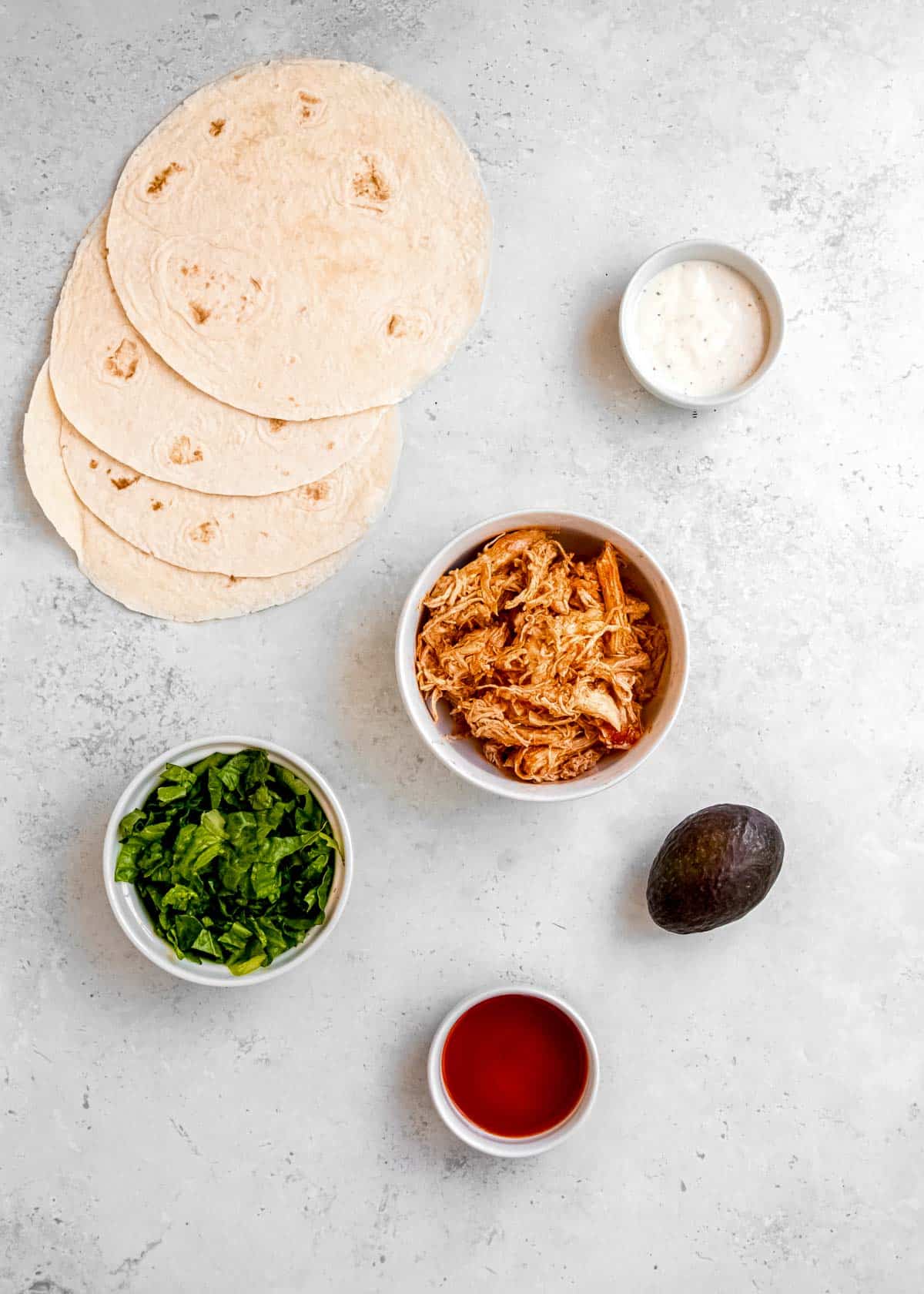 overhead image of buffalo chicken wrap ingredients on a white table