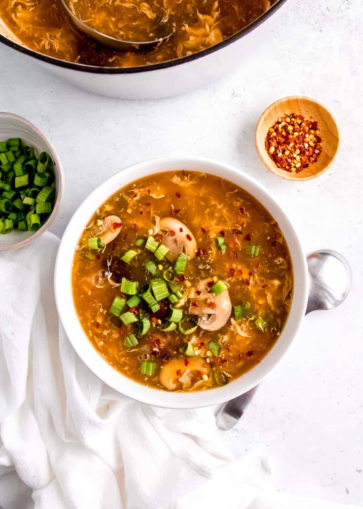 overhead image of hot and sour soup in white bowl on white table