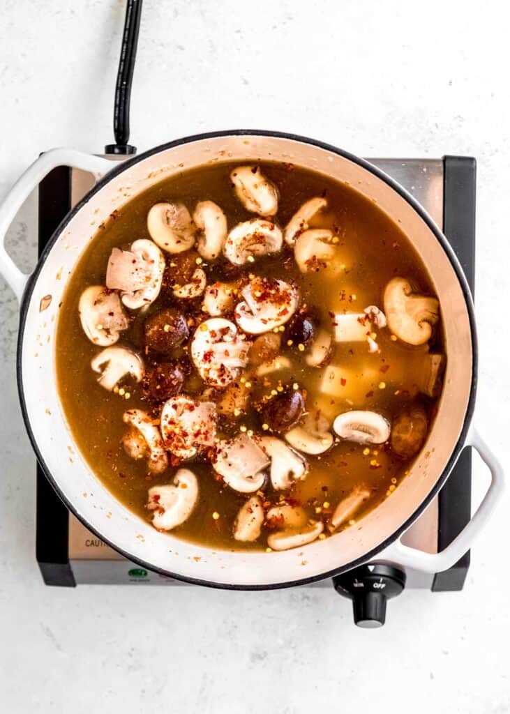 mushrooms, ginger, and broth simmering in dutch oven