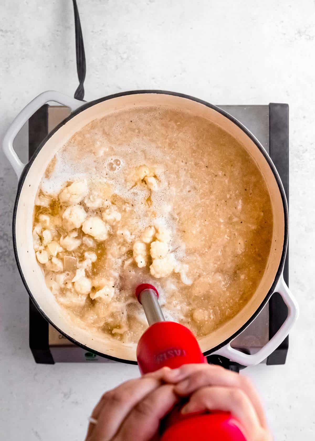 cauliflower soup being blended in dutch oven