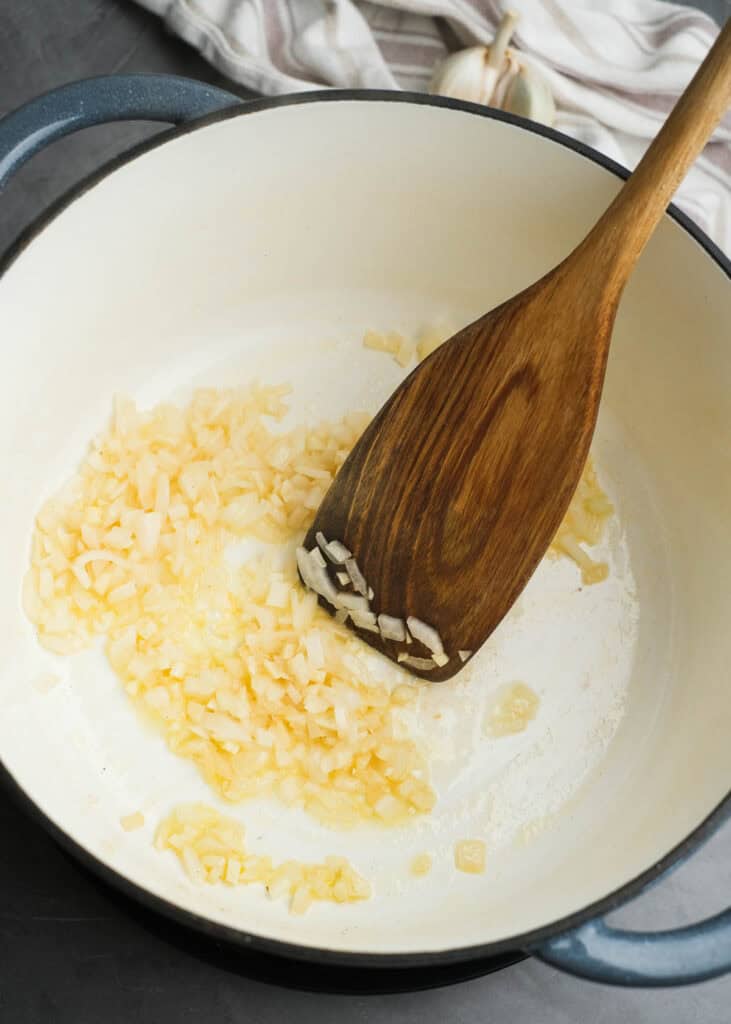 onions and garlic being sauteed in dutch oven