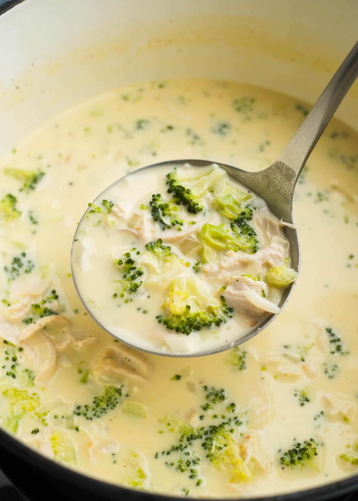 overhead image of a spoonful of broccoli cheese soup being removed from dutch oven