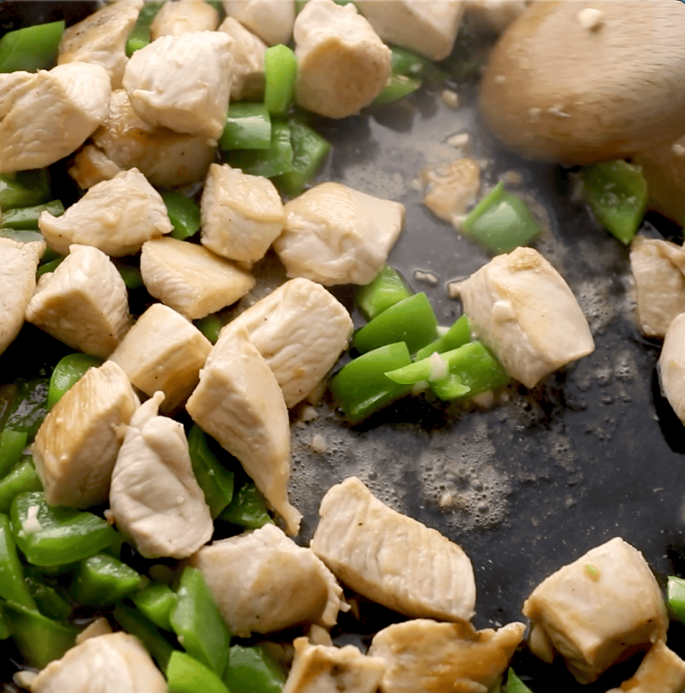 broth being added to chicken and bell pepper in skillet