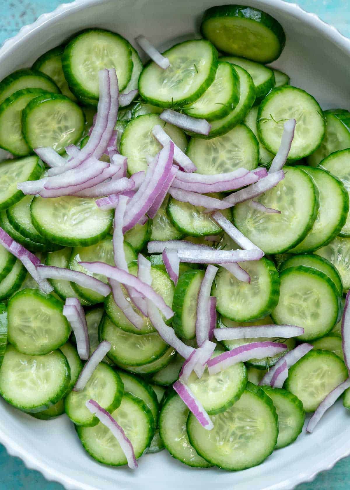 overhead image of onions being mixed with sliced cucumbers