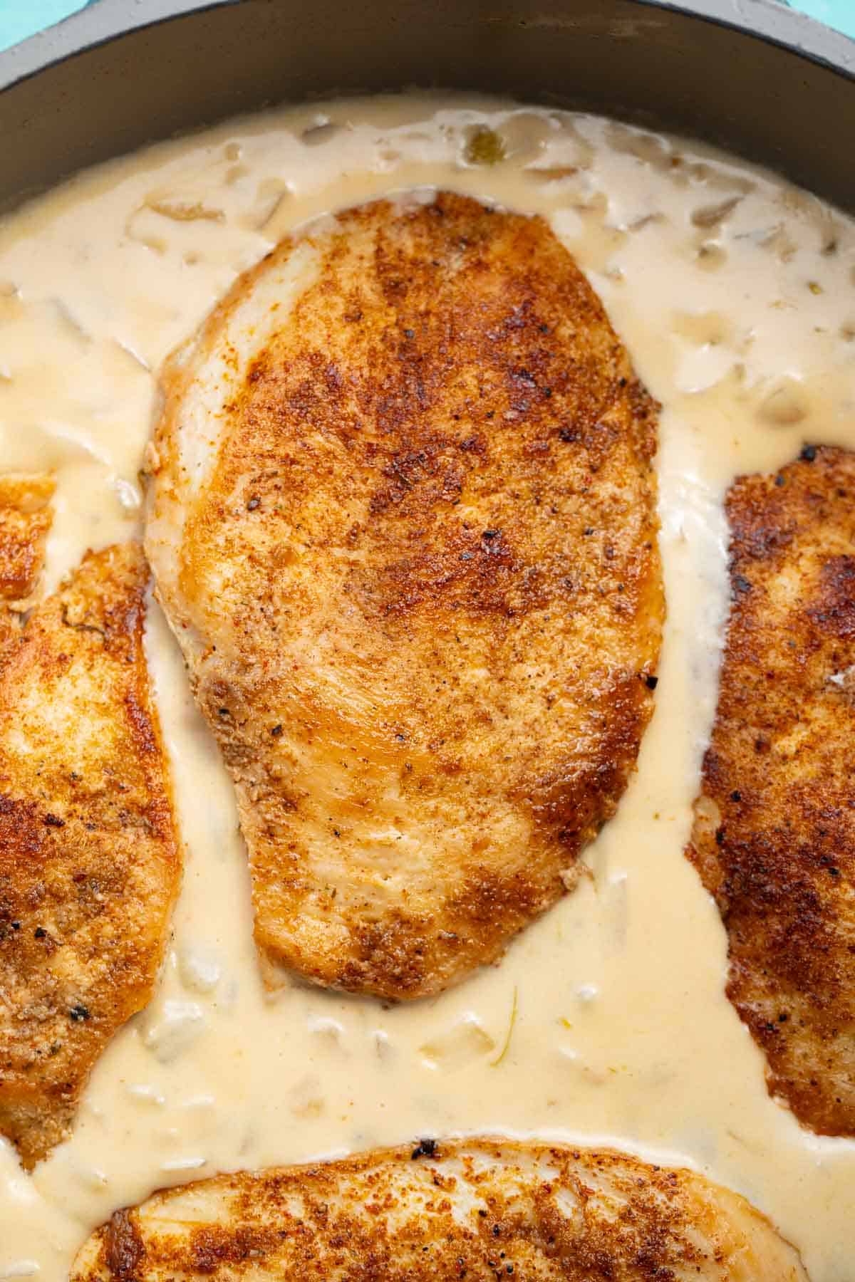 seared, seasoned chicken in a creamy sauce in a skillet