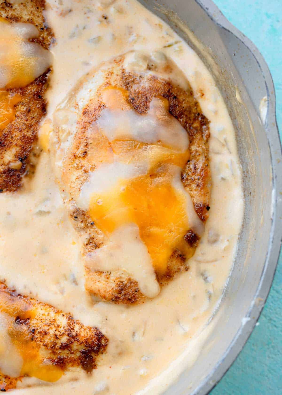 shredded cheese melted onto a chicken cutlet in creamy green chili sauce