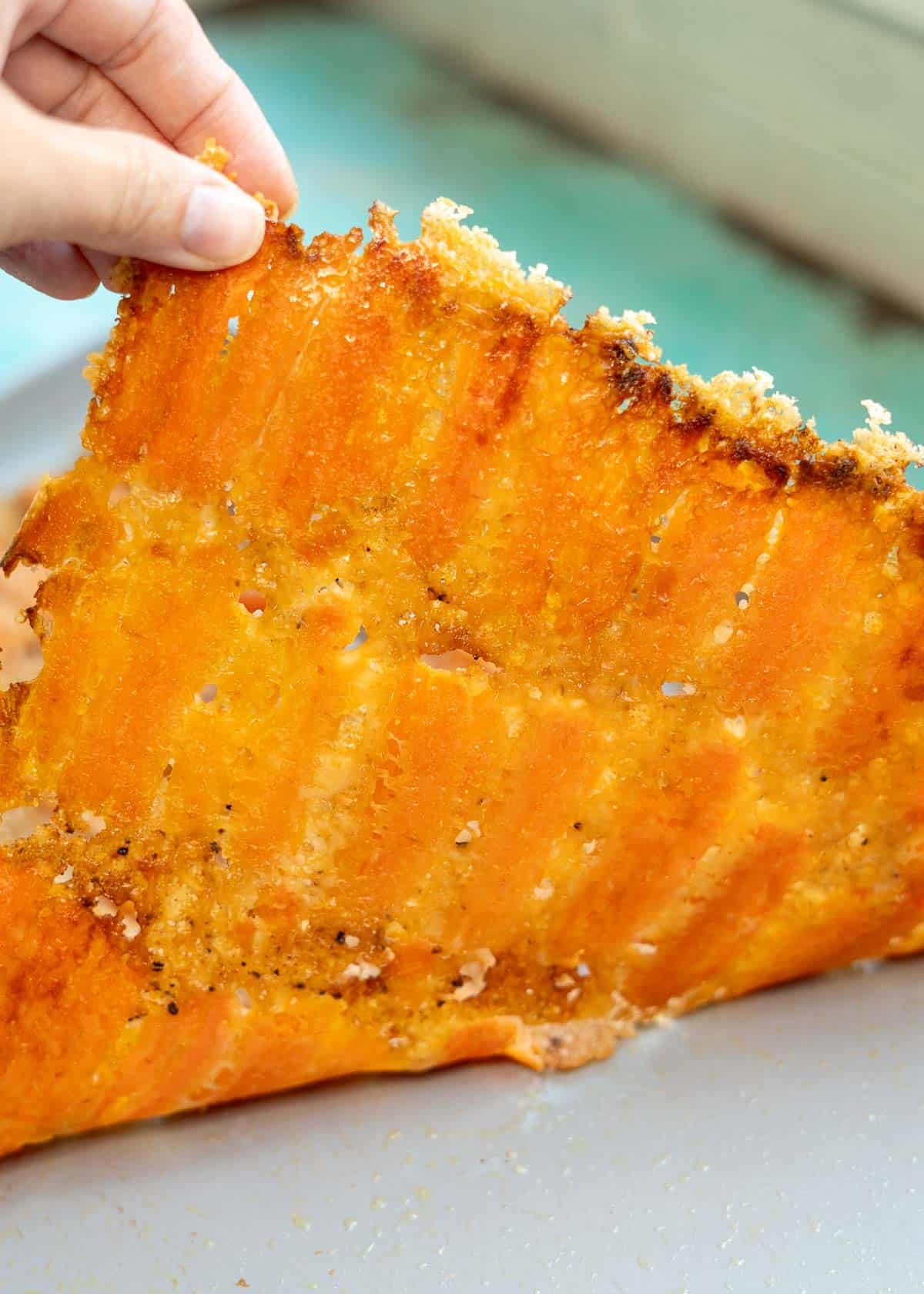 smashed, cooked carrots being peeled from sheet pan